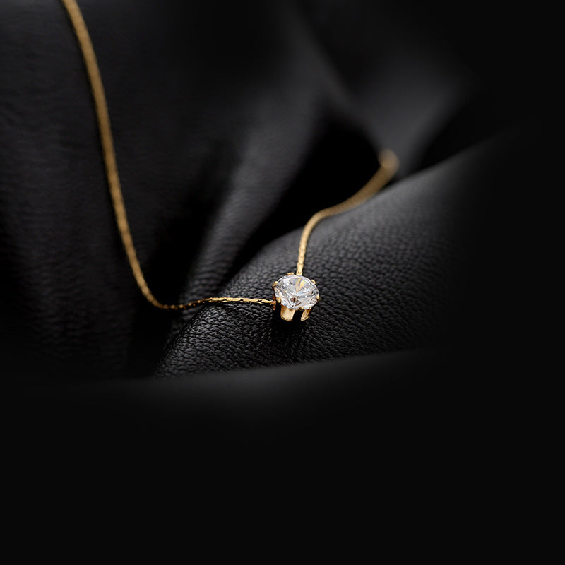 A gold-plated round rhinestone pendant necklace resting on a textured surface, highlighting its delicate design and inlay of artificial rhinestones. Lilyah Jewelry Gold Plated Necklace. Gift Ideas for her.