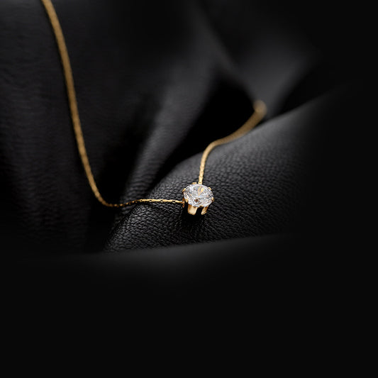 A gold-plated round rhinestone pendant necklace resting on a textured surface, highlighting its delicate design and inlay of artificial rhinestones. Lilyah Jewelry Gold Plated Necklace. Gift Ideas for her.