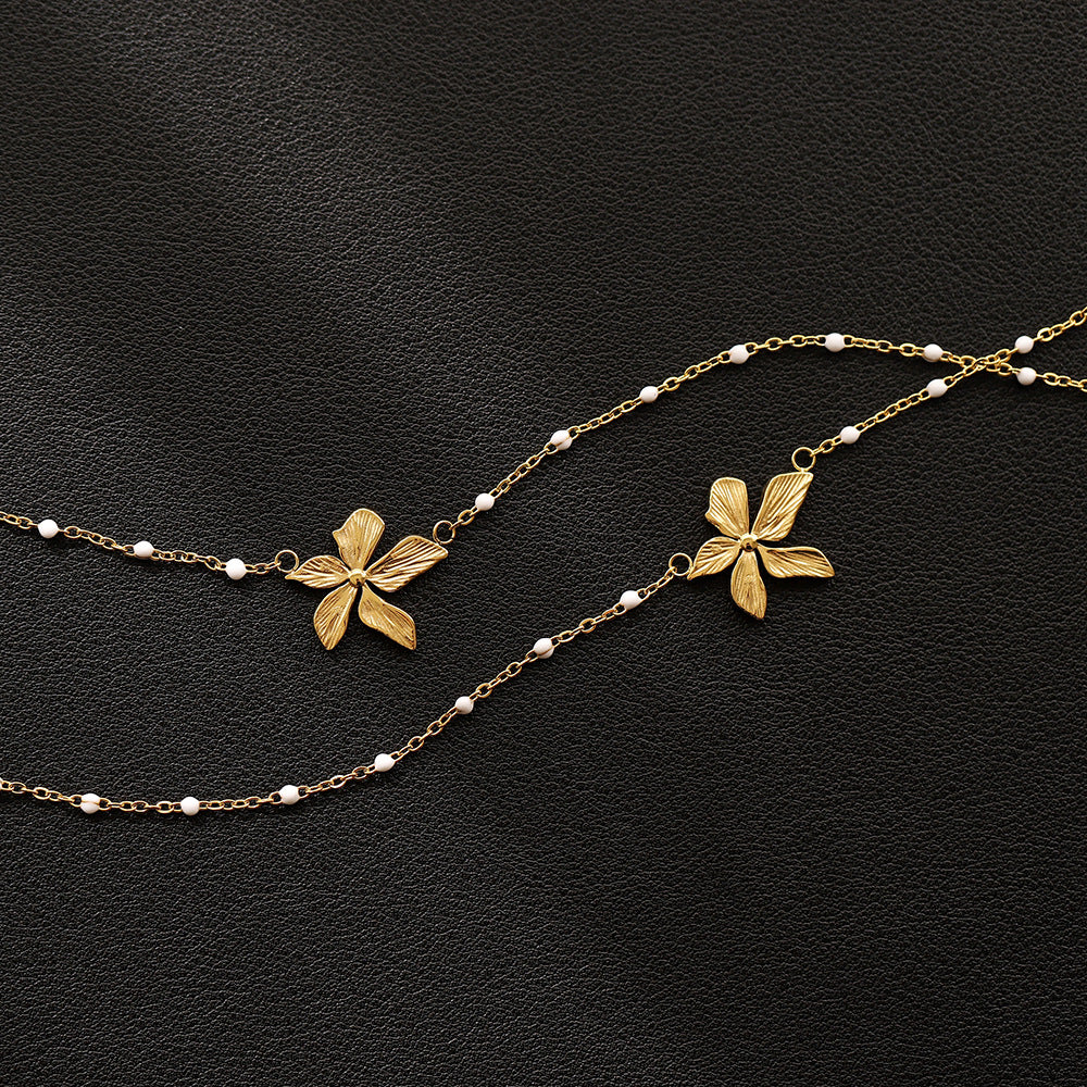 18k Goldplated floral necklace with white bead accents on a black background