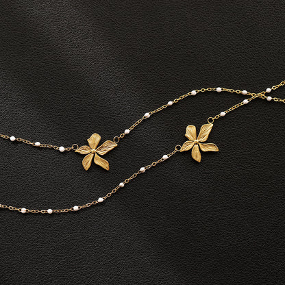 18k Goldplated floral necklace with white bead accents on a black background