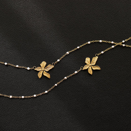 18k Goldplated floral necklace with white bead accents on a black background