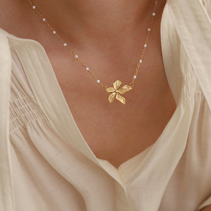 18K Gold Plated necklace with a floral pendant worn by a person in a light-colored top.