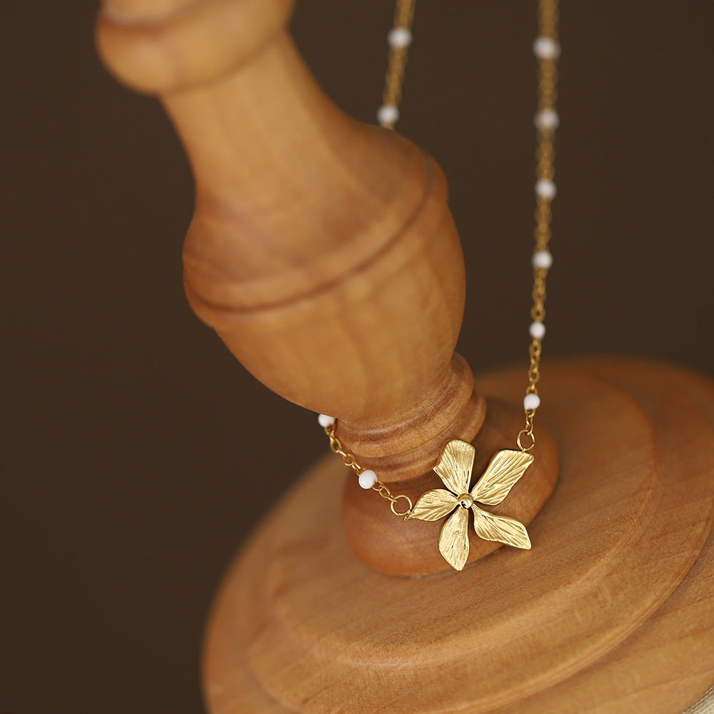 Gold plated necklace with a floral pendant on a wooden stand