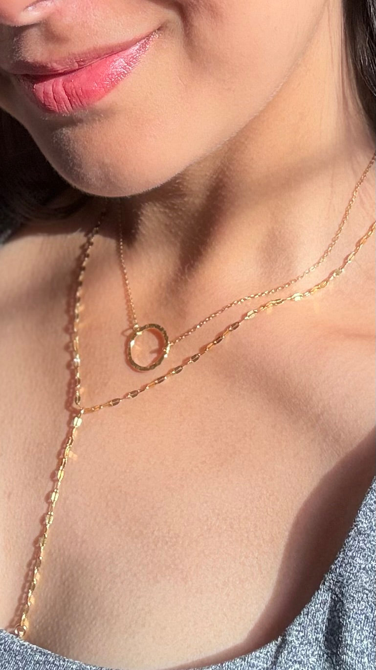 Close-up of a person wearing a gold plated two layered necklace with a circular pendant and a Y shape necklace. It is delicate and pretty. The necklace set is detachable. 