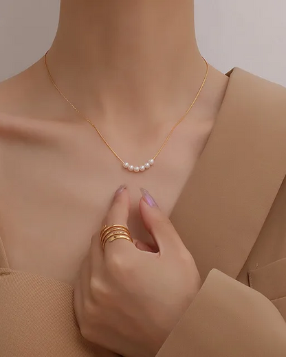 A person wearing a beige top showcasing a gold-plated necklace with artificial pearls. Lilyah Jewelry Gold Plated Necklace. Gift Ideas for her.