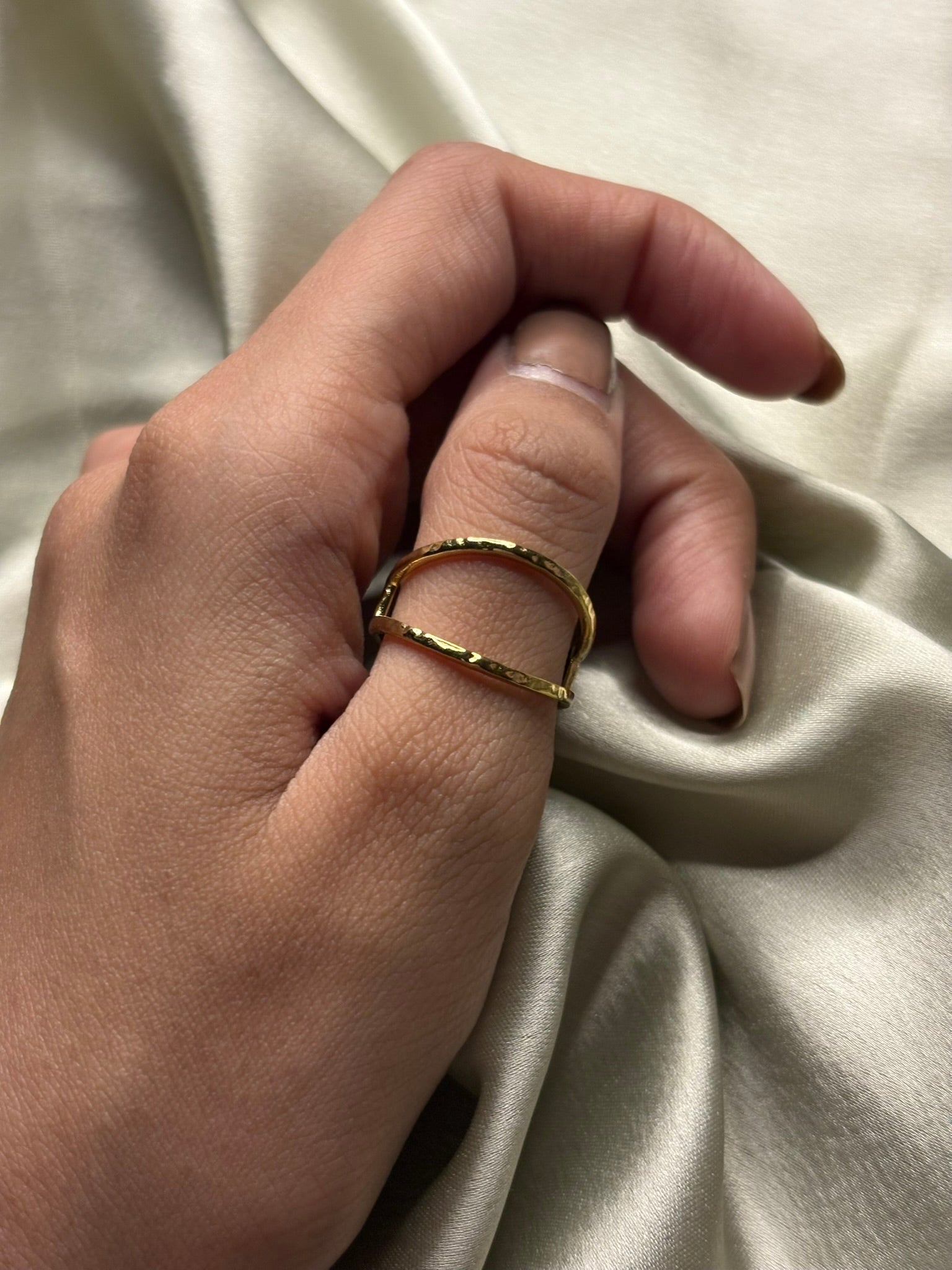 Hand wearing a gold ring on a beige fabric background. Lilyah Jewelry Gold Plated Ring . Stunning, minimalistic, adjustable, elegant and statement ring. Gift idea for her.