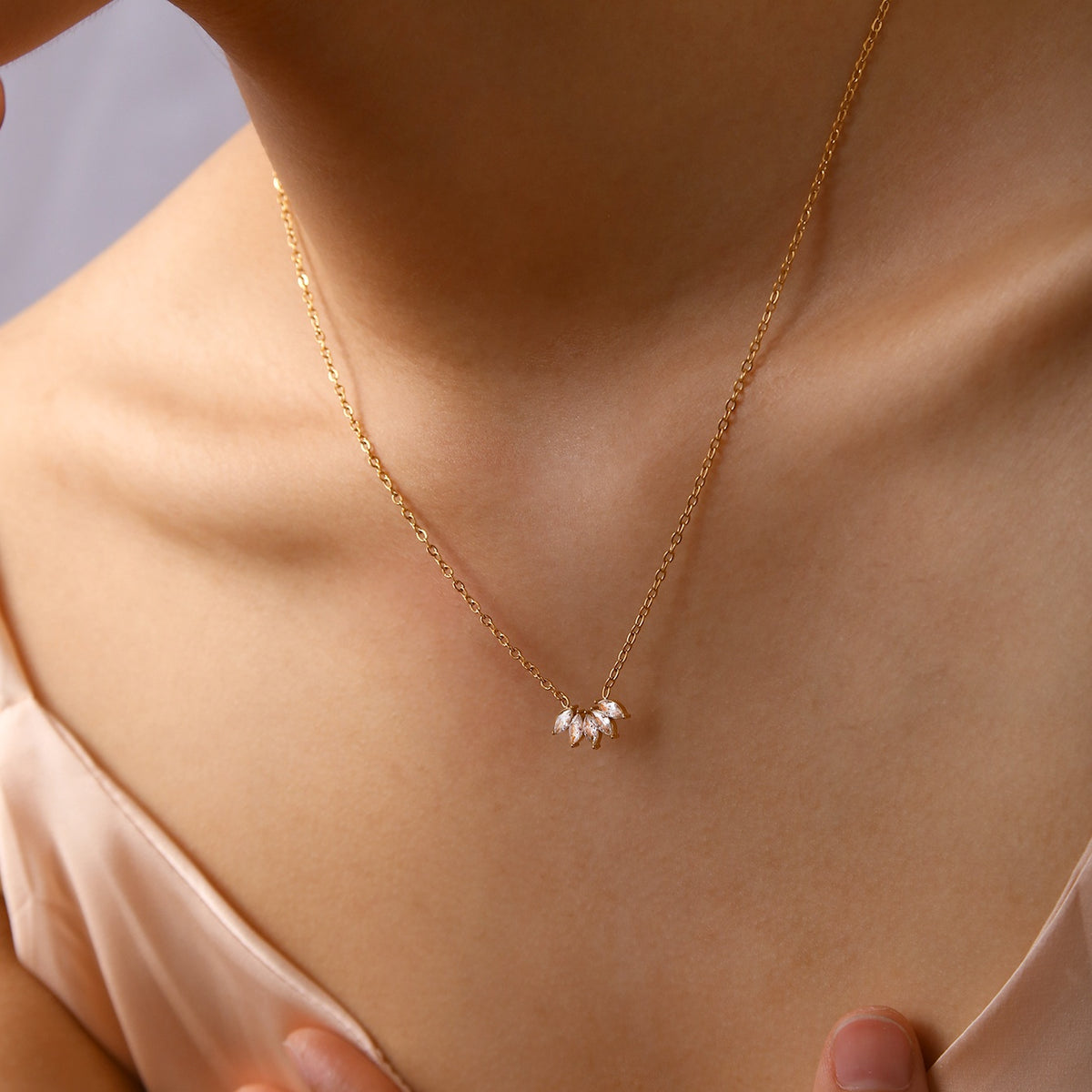 Lilyah Jewelry's 18K Gold Plated necklace with a delicate pendant that look like petals on a person wearing a light pink top.