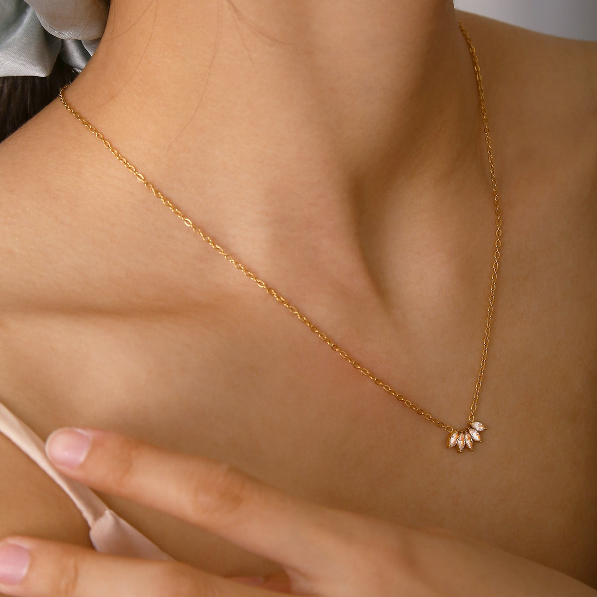 Lilyah Jewelry's 18K Gold Plated necklace with a delicate pendant that look like petals on a person wearing a light pink top.