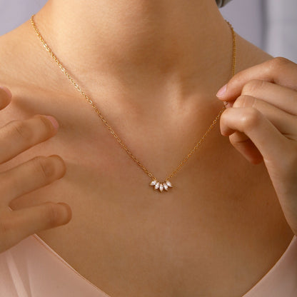 A close-up lifestyle shot of a model wearing a Lilyah Jewelry's delicate 18k gold plated chain necklace with a small cluster of rhinestone petals at the center, styled with a soft pink top.