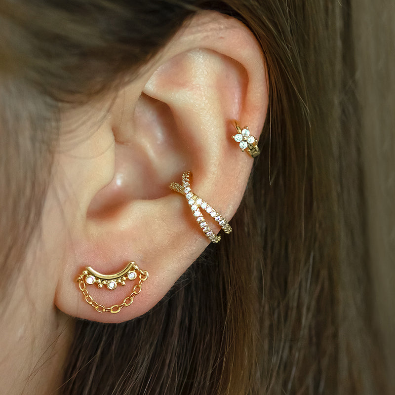 Close-up of an ear with Lilyah Jewelry's 18K gold plated earrings on a blurred background