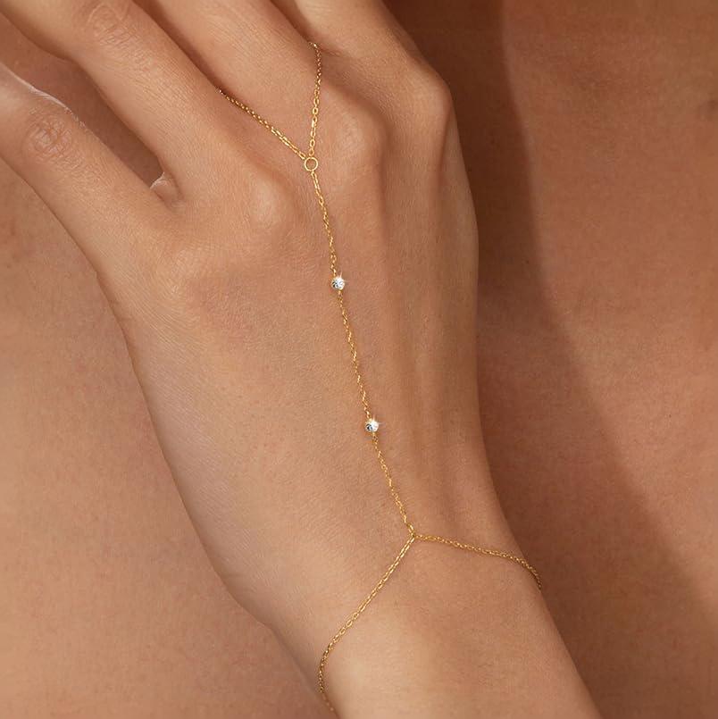 Lilyah Jewelry's delicate 18k gold plated hand bracelet with three small white zircon diamonds, shown worn on a model's hand against a warm skin-toned background.