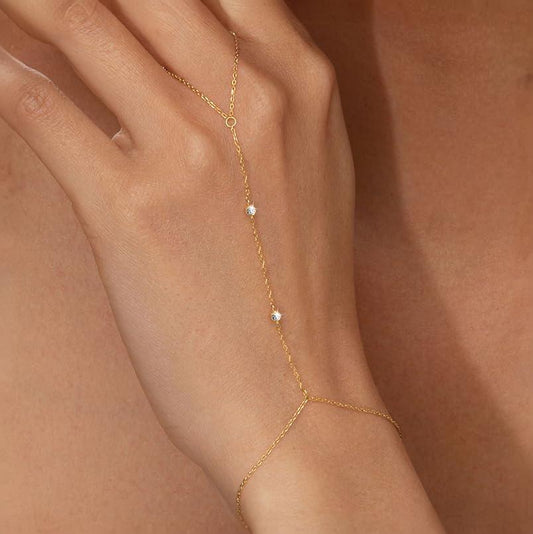 Lilyah Jewelry's delicate 18k gold plated hand bracelet with three small white zircon diamonds, shown worn on a model's hand against a warm skin-toned background.