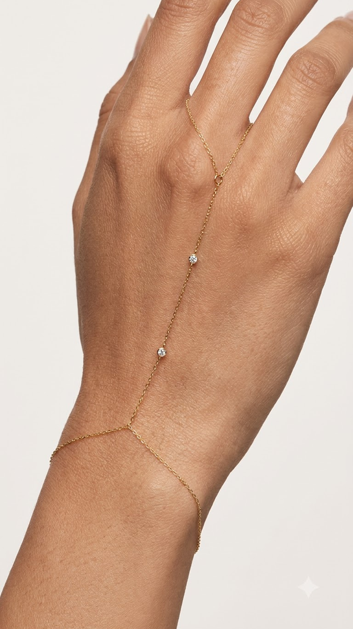 Lilyah Jewlery's delicate 18k gold plated ring and hand bracelet with three small clear gemstone accents, shown worn on a person's hand against a light off-white background