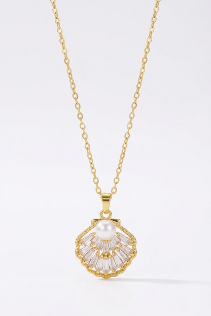 A gold chain necklace with a scallop-shaped pendant featuring a white pearl at the center and clear baguette-cut stones radiating from a gold setting, shown on a clean white background.