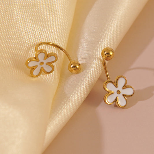 Lilyah Jewelry's 18k gold-tone flower-shaped earrings with white enamel centers, displayed on draped cream satin fabric.