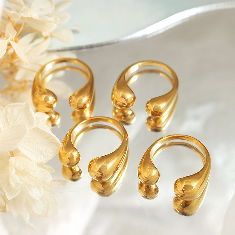 A collection of gold-plated stainless steel open rings displayed on a reflective surface, with a floral pattern in the background. Lilyah Jewelry Gold Plated Ring . Stunning, minimalistic, adjustable, elegant and statement ring. Gift idea for her.