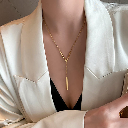 A person wearing a white blazer and a black top, showcasing a gold-plated minimalistic V-necklace. Lilyah Jewelry Gold Plated Necklace. Gift Ideas for her.