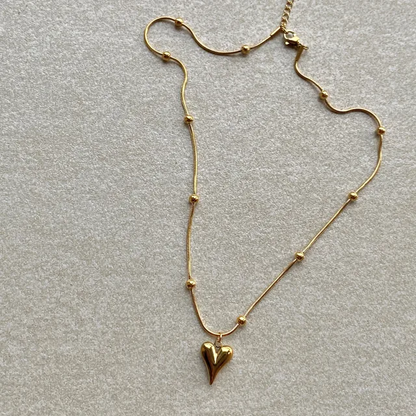 Lilyah Jewelry Necklace. Gold necklace with a heart pendant on a light gray background