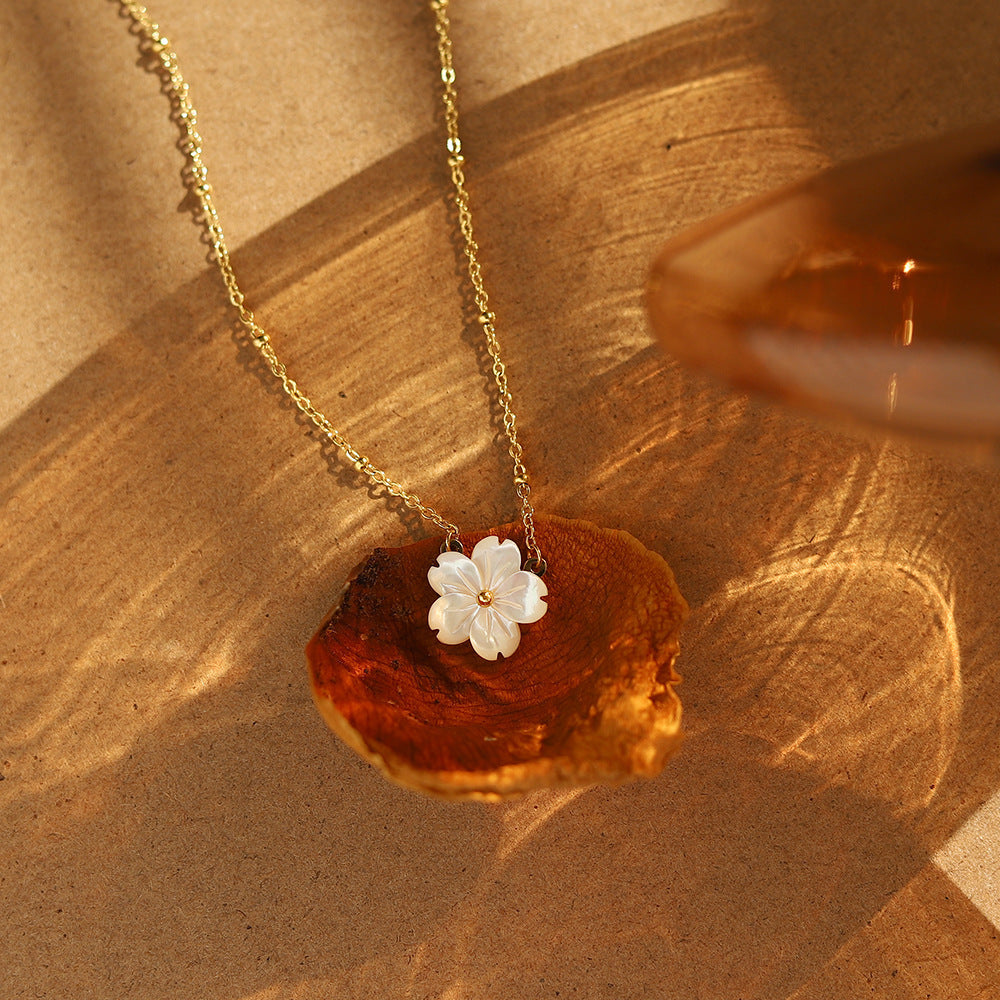 Necklace with a white flower pendant on a brown surface