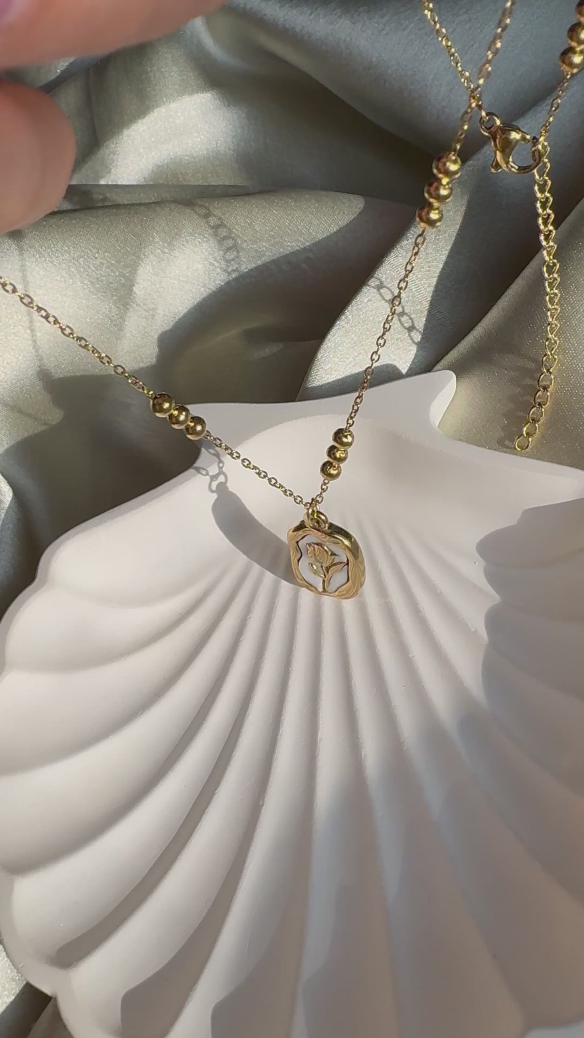 Lilyah Jewelry Necklace video. Under Sunlight. the necklace is golden in colour and has a rose pendant.
